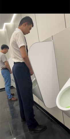 A handsome and cute boy is pissing in the toilet.