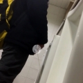 A male is pissing in the toilet.